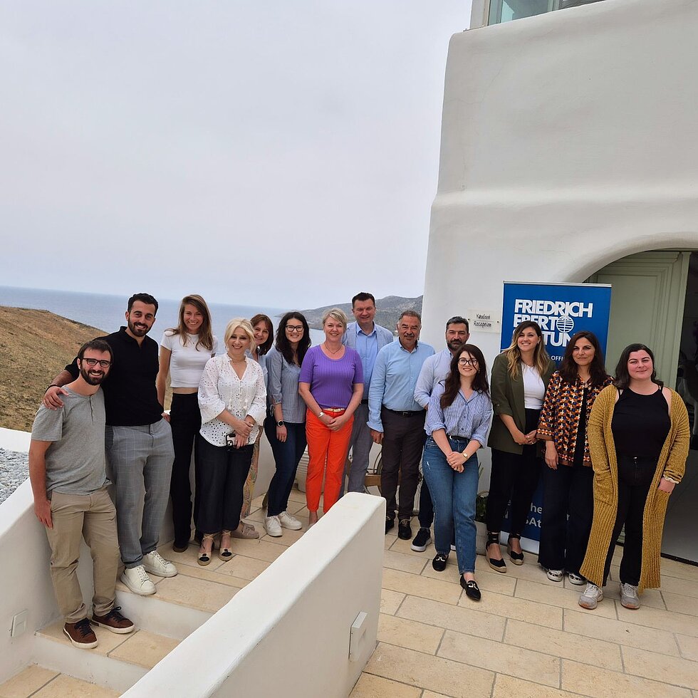 Group photo of fourteen people on a terrace in front of Friedrich Ebert Stiftung conference banner.